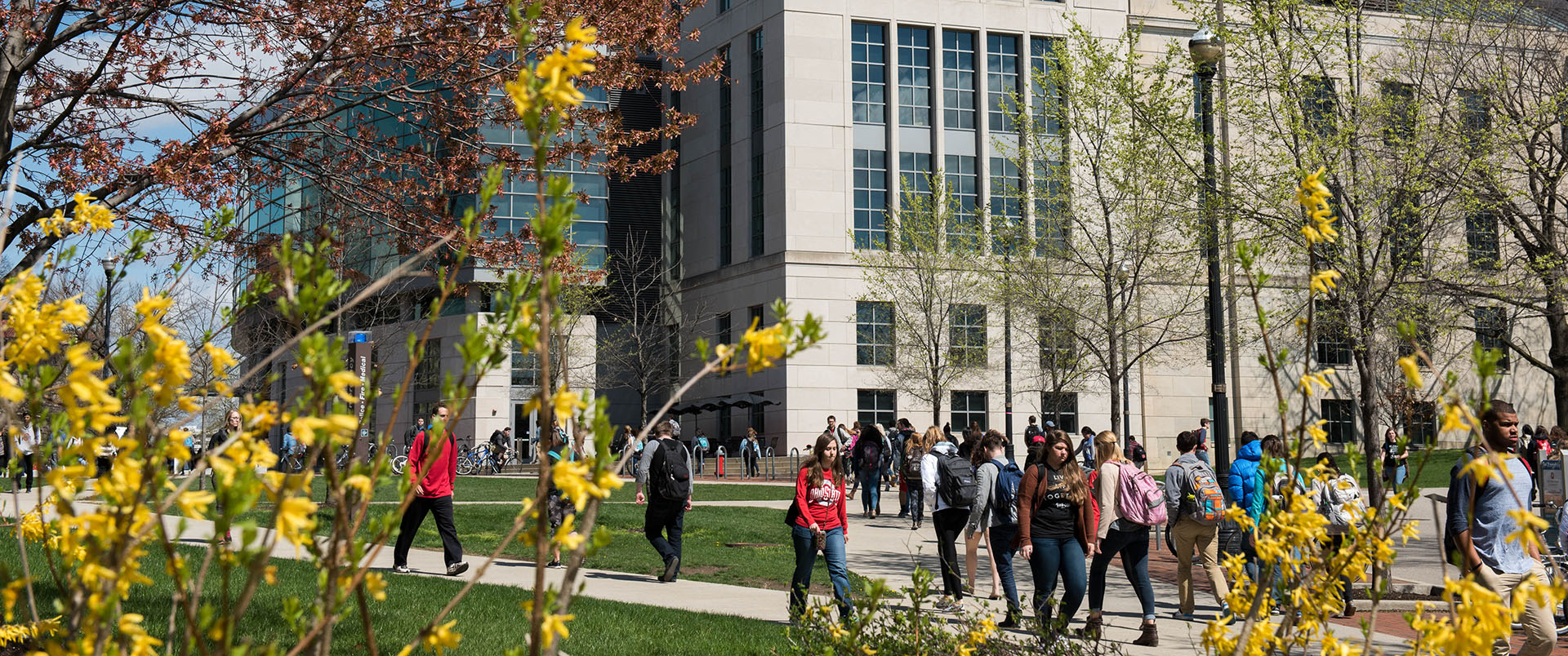 Spring flowers are in bloom while students walk in front of Thompson Library on Ohio State's Columbus campus.