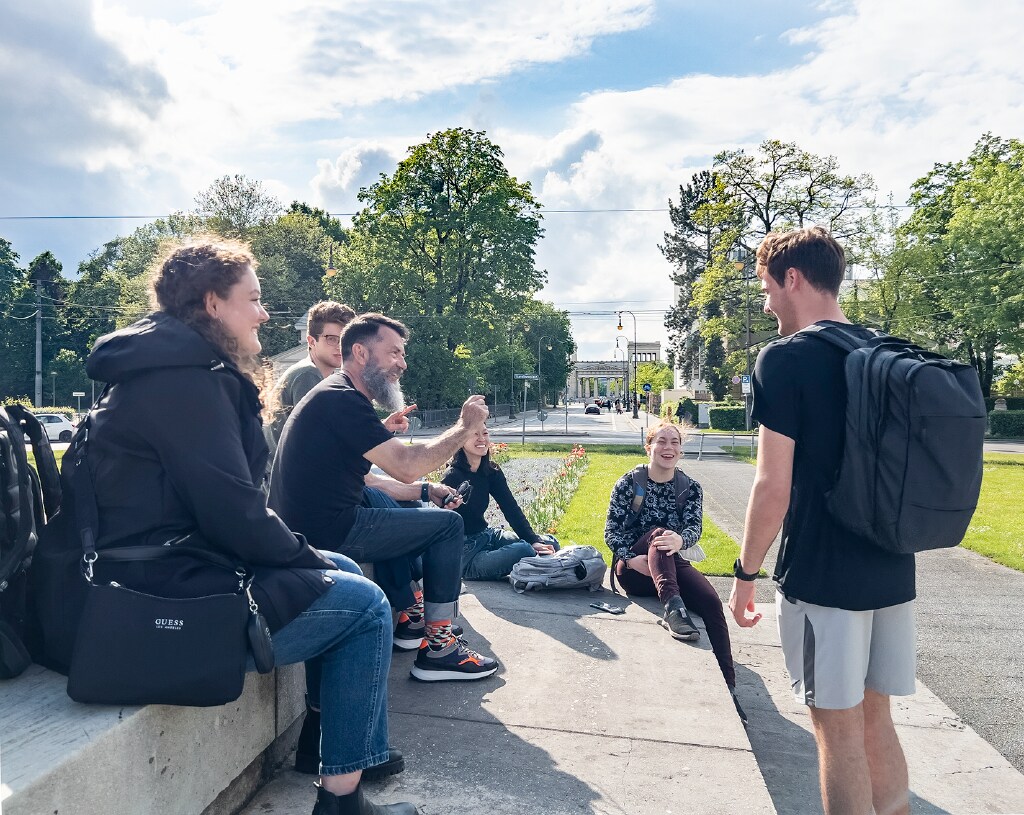 An instructor lectures to a small group of students outside on campus.