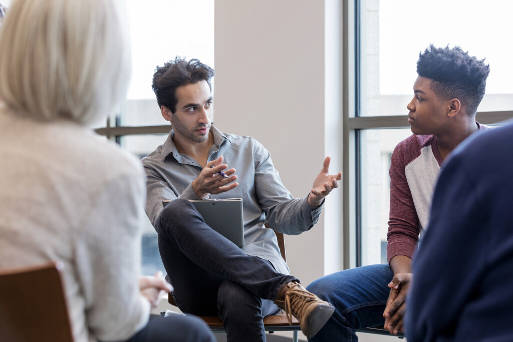 A professor speaks with a group of students in a classroom.