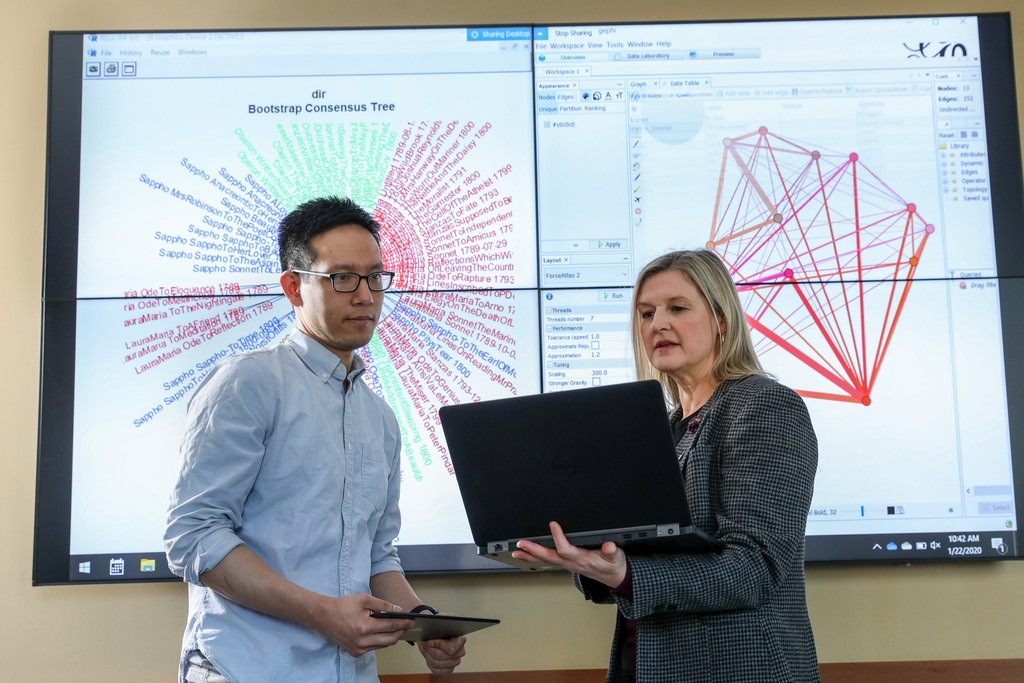 Two faculty members consult in front of a large scientific image.