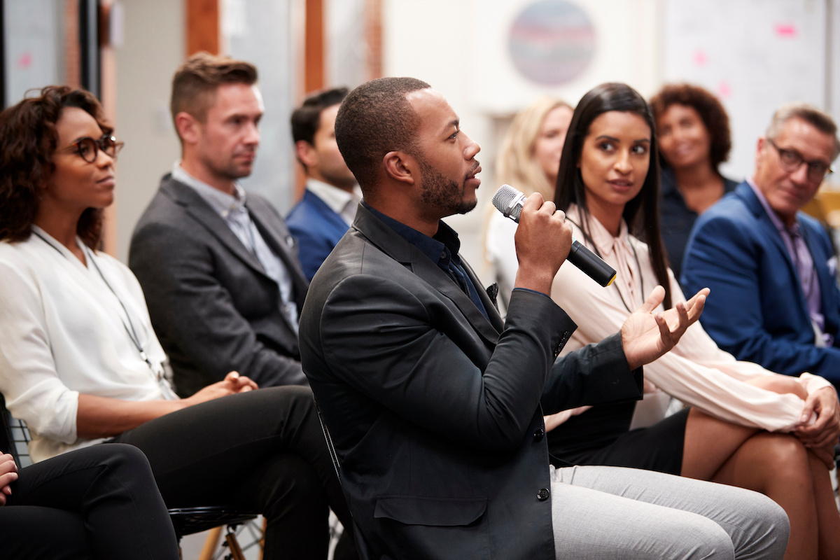 A young man asks a question at a conference.