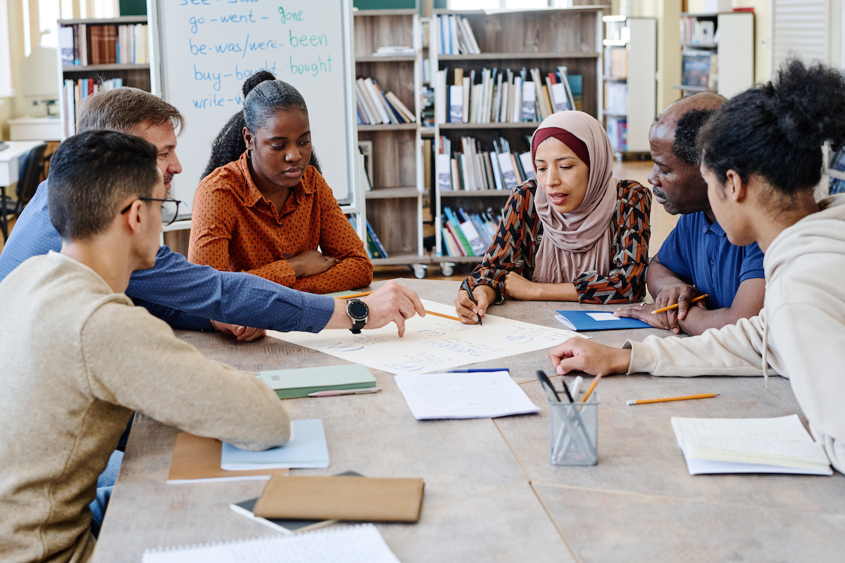 A group of faculty sit around a table and conference.