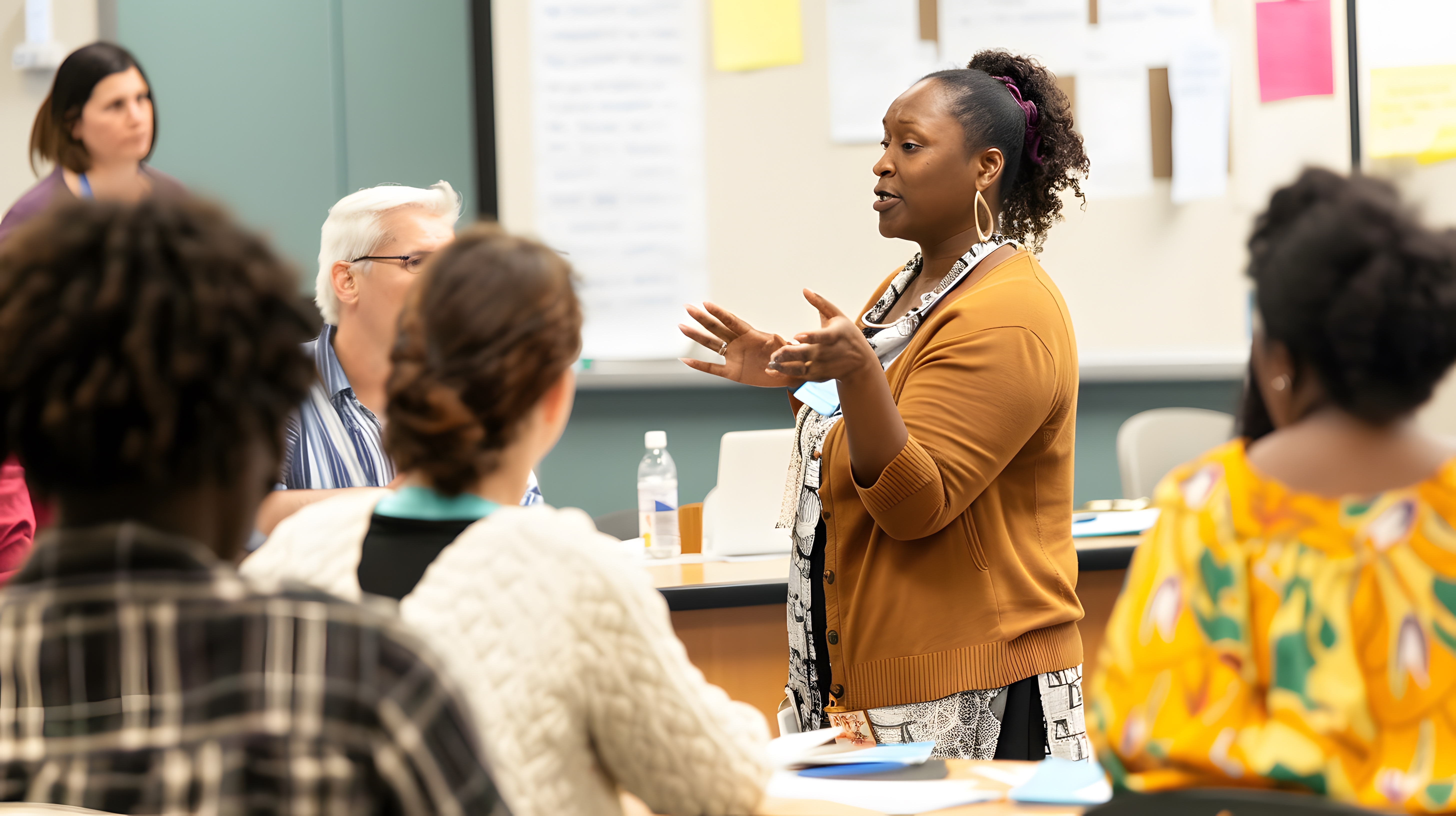 A group of adult learners in discussion in a classroom.