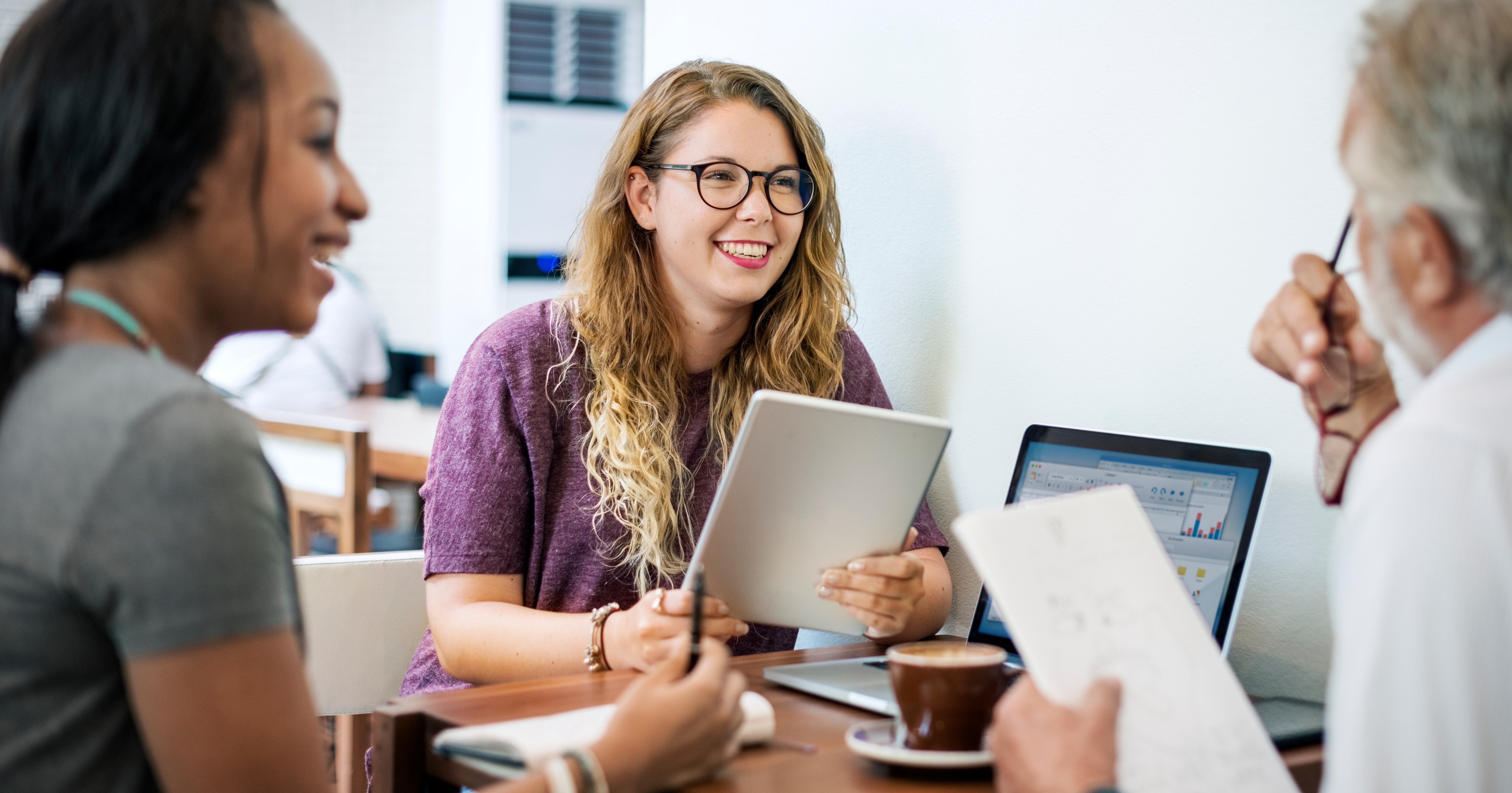 Three instructors seated around a table in discussion