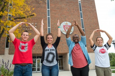 Group of Ohio State students signaling O-H-I-O with their arms above their heads.