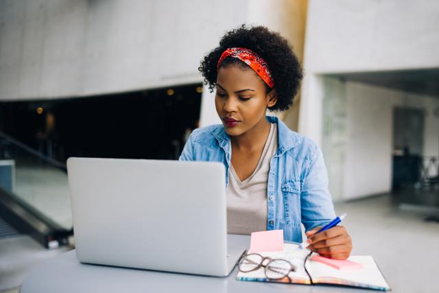 An instructor looks at a laptop while taking notes.
