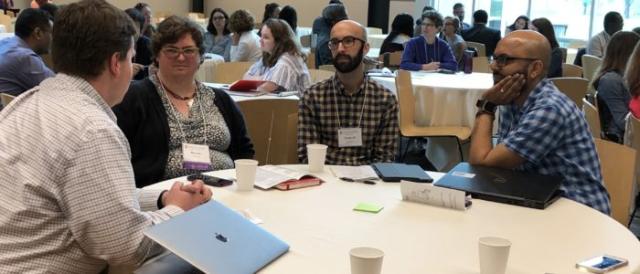 Four conference attendees in discussion at a round table.