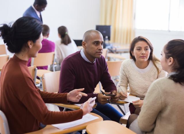 A small group of instructors have a discussion in a classroom.