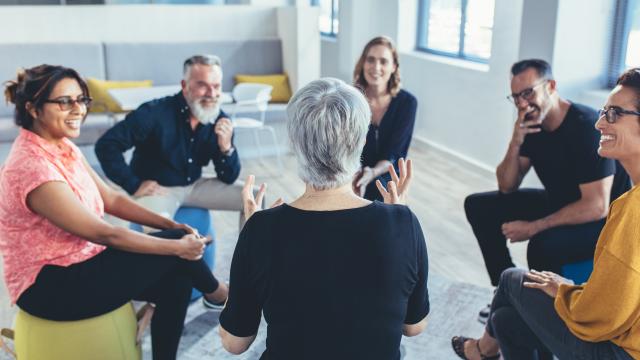 A group of instructors sits in a circle talking.