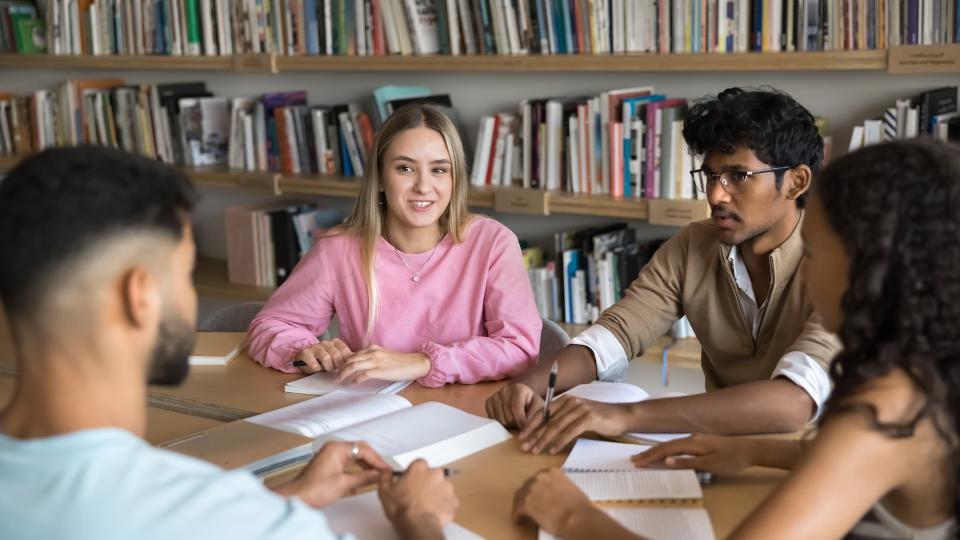 Graduate students sit around a table in discussion.