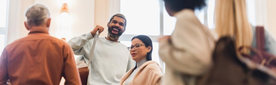 A smiling student puts on his backpack and talks to peers at the end of class.