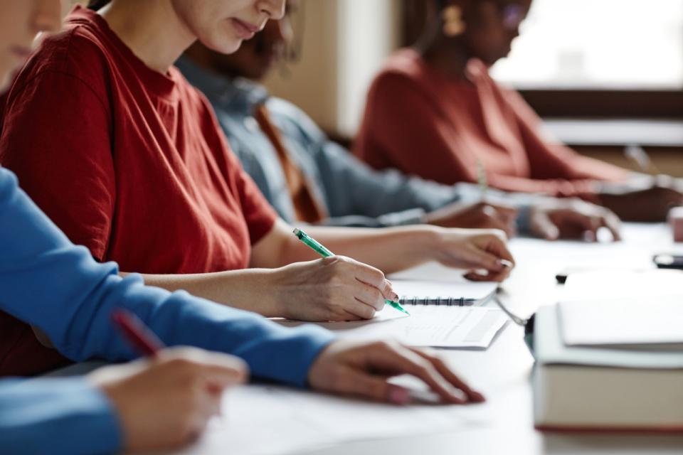 A row of students filling out a survey in a brightly lit classroom
