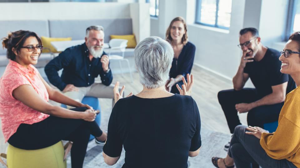 A group of instructors sits in a circle talking.