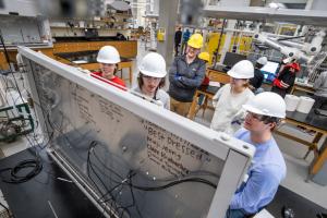 Group of students with hard hats around white board