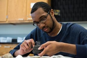 Student examining fossil with magnifying glass