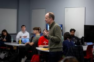 A professor speaks with a class in a medium sized classroom.